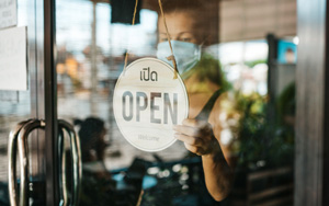 covid-masked-woman-using-open sign on a store window