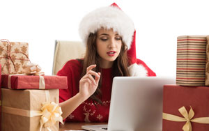 woman on laptop wearing santa hat