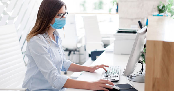 masked woman working on a computer