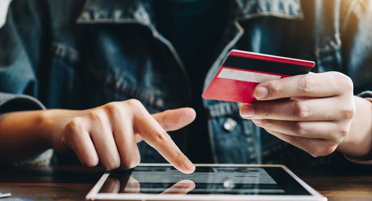 shopping on a tablet with a credit card in hand