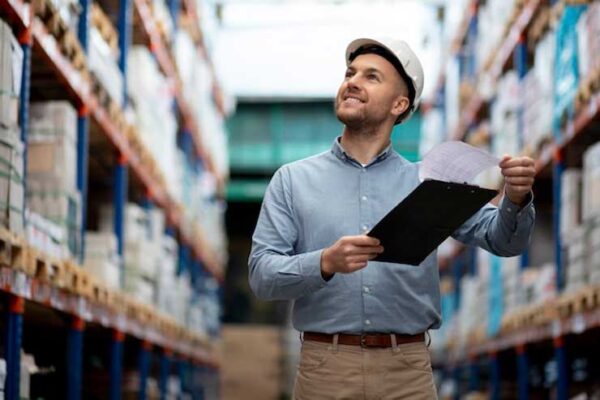 worker with clip-board inspecting warehouse products